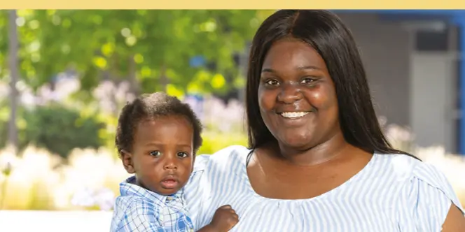 The image shows a smiling woman holding a toddler, both in light blue clothing, in an outdoor setting with blurred greenery and flowers in the background. The atmosphere is bright and cheerful, conveying a sense of warmth and positivity.